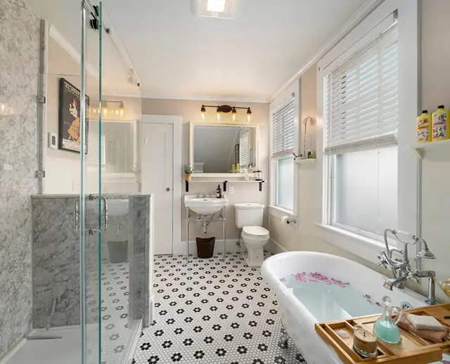 Newport, RI bathroom with a clawfoot tub, frameless glass shower, black and white floral floor tile and a pedestal sink