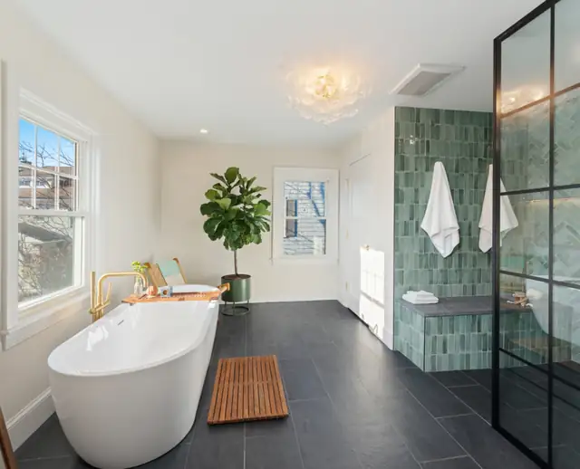 Providence, RI bathroom with a white freestanding tub, brass tub filler, green tile shower behind black steel-framed glass and dark slate floor