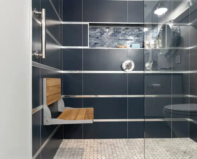 Bristol, RI primary bathroom with a zero-entry shower, navy wall tile, a fold-down teak shower seat and basketweave mosaic floor